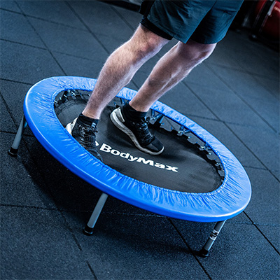 Close-up angled view of a user stepping onto the BodyMax Mini Fitness Trampoline in blue 