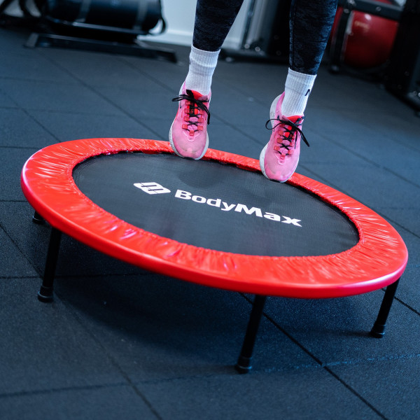 Close-up top view of a user’s feet performing quick bounce jumps on the BodyMax Mini Fitness Trampoline in red