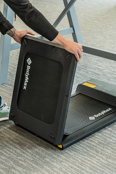 User lifting the BodyMax WP60 Treadmill to fold it