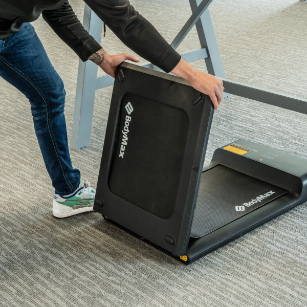 User lifting the BodyMax WP60 Treadmill to fold it