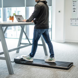 User walking on the BodyMax WP60 Treadmill while working at a desk