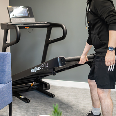 User unfolding the BodyMax TM70 treadmill deck