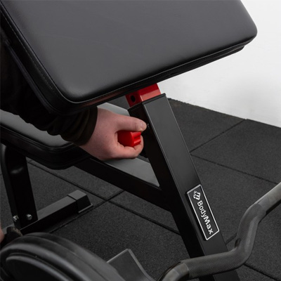 Lifestyle image of a model adjusting the BodyMax CF625 Heavy Duty Preacher Curl Bench