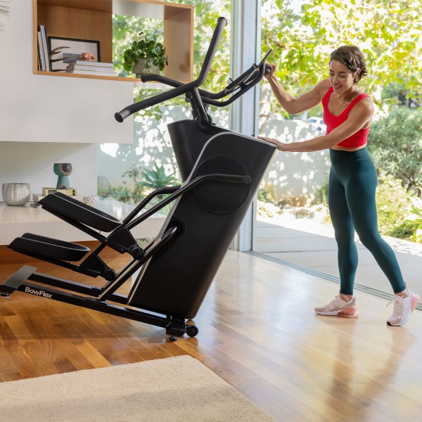 A user moving the BowFlex Max Trainer SEi using its transport wheels