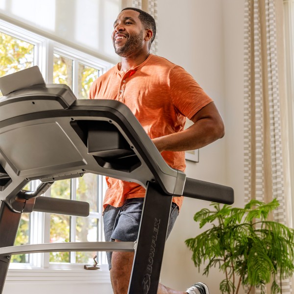 Person jogging on the BowFlex BXT8Ji Folding Treadmill near a window