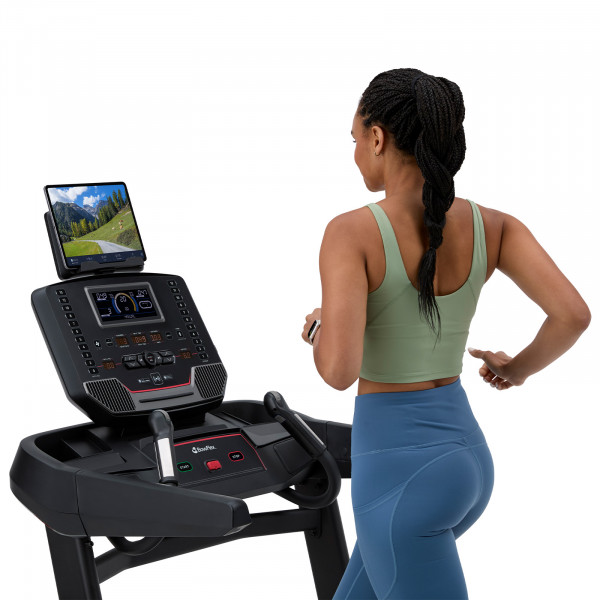 Person running on the BowFlex T9 treadmill while using a fitness app.
