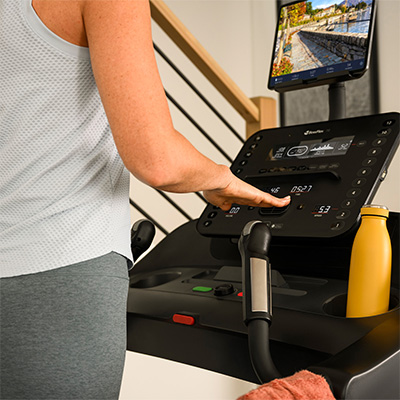 Person adjusting speed and incline using QuickDial™ controls on the BowFlex T6 treadmill