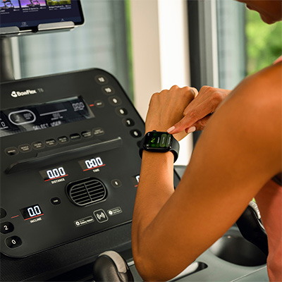 Person checking smartwatch while using the BowFlex T6 treadmill