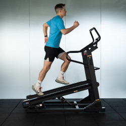 A studio image of the cardiostrong IT70 Incline Treadmill showing a model running on the incline treadmill