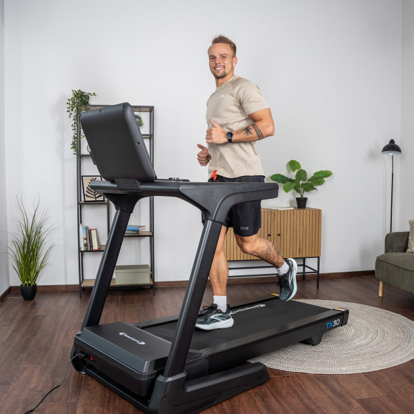 User running on the cardiostrong TX30 Treadmill in a home gym