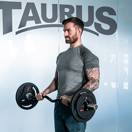 A person performing a supine bicep curl with a Taurus EZ Barbell.