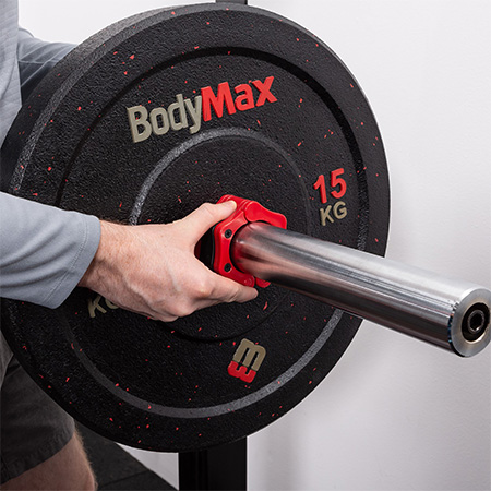 Person placing a BodyMax 15kg Olympic Rubber Crumb Bumper Weight Plate on a barbell with a red collar