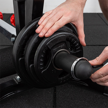 Person securing BodyMax Olympic Rubber Radial Disc Weight Plates on a barbell with a spring collar.