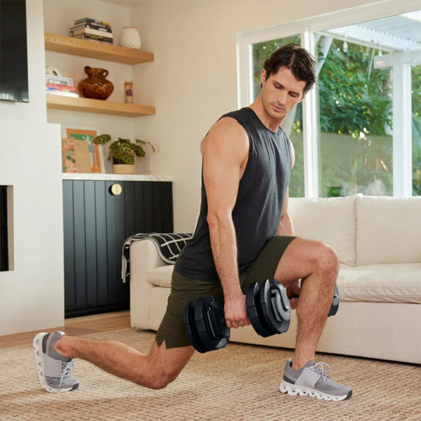 Person doing a lunge with the Centr Smart Stack 50 Adjustable Dumbbells.