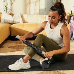 Person using a massage roller stick from the Centr Recovery Kit.
