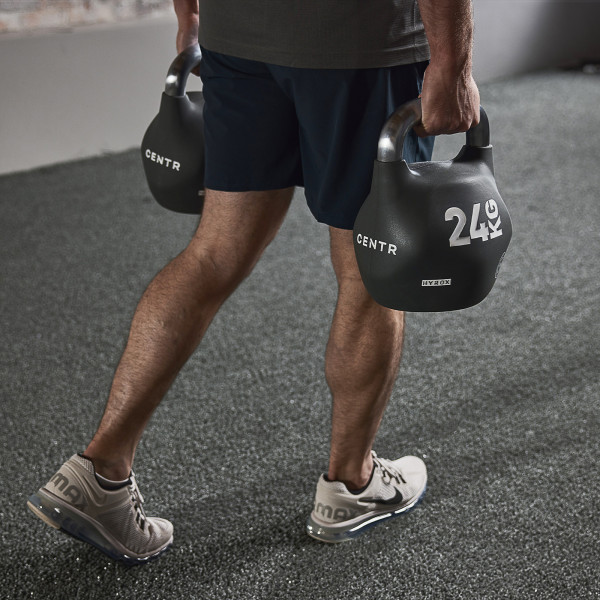 Lifestyle image of a model using the 24kg CENTR x HYROX Competition Octo Kettlebell in a farmer's carry exercise.