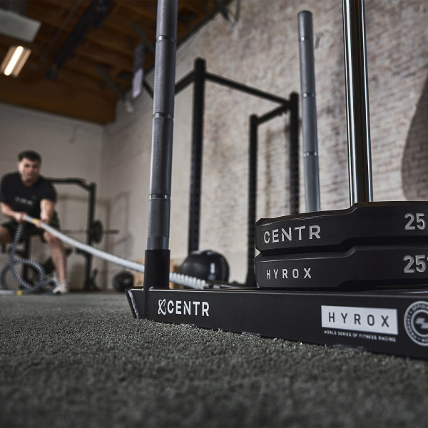 CENTR x HYROX Bumper Plates stacked on a sled in a gym setting.