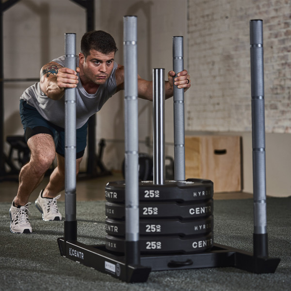 Person pushing sled loaded with CENTR x HYROX Bumper Plates.