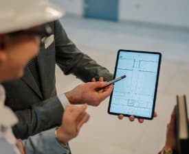 A person shown another person a layout of a room on a tablet.