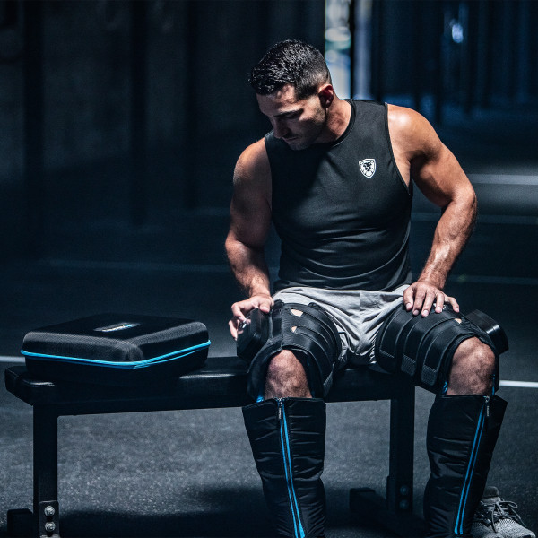 Lifestyle image of the Compex Ayre Compression Boots - Model is sat on a bench
