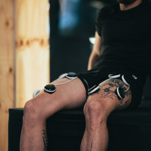 Lifestyle image of the Compex SP 6.0 - It shows the wireless dots on the model's legs.