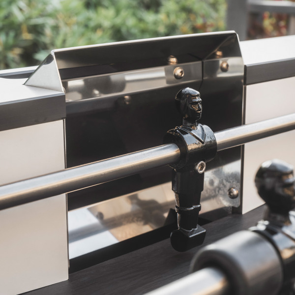 Black player figure near stainless steel goal on the Cornilleau Play-Style Origin outdoor football table in white
