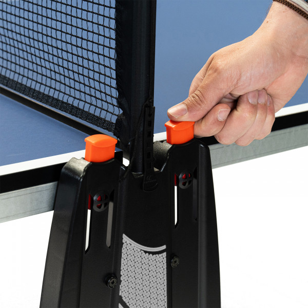 Hand pressing the orange safety button on the Cornilleau Challenger Indoor Table Tennis Table