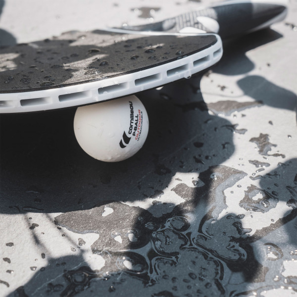 Close-up of an outdoor bat and ball on the black Cornilleau Play-Style Origin table