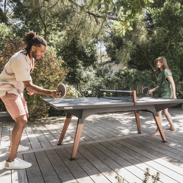 Two people playing on the black Cornilleau Play-Style Origin Medium Outdoor Table Tennis Table
