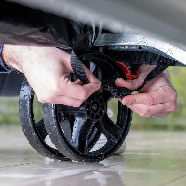 Close-up of a hand securing the cover near the wheel