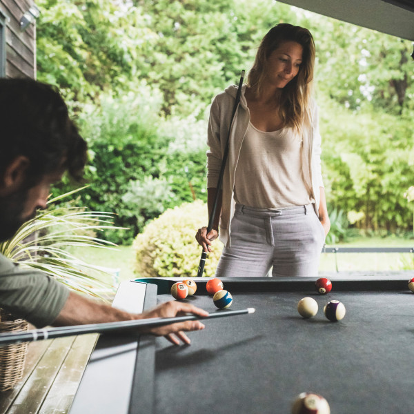 People playing on the Cornilleau Play-Style Hyphen outdoor pool table with black frame and light grey cloth