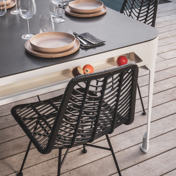 Close-up of the Cornilleau Play-Style Hyphen pool table in dining setup with plates and cues stored beneath