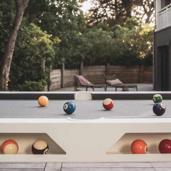 Side view of the Cornilleau Play-Style Hyphen outdoor pool table with white frame and dark grey cloth