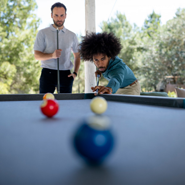 Focused shot of a player taking aim on the Cornilleau Play-Style Hyphen outdoor pool table with white frame and light grey cloth