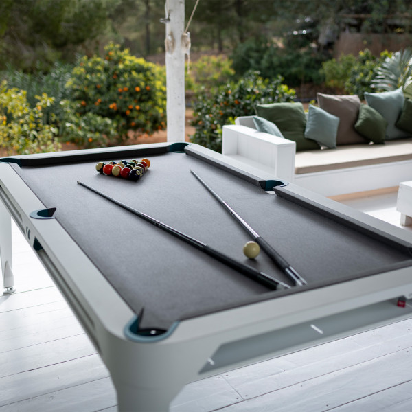 Outdoor setup of the Cornilleau Play-Style Hyphen pool table with balls racked and cues placed on the cloth