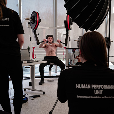 Image of a team of sports scientists working with an athlete to assess machine performance