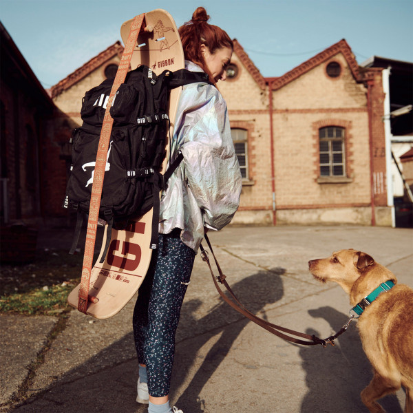 Person walking dog with Gibbon Giboard Set Roots Rocker Travel on backpack