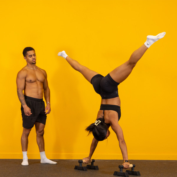 Gravity Fitness Travellettes - Lifestyle image - Model performing a handstand with the splits.