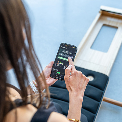 Model using the Gymproluxe Portable Pilates Reformer app during a workout 