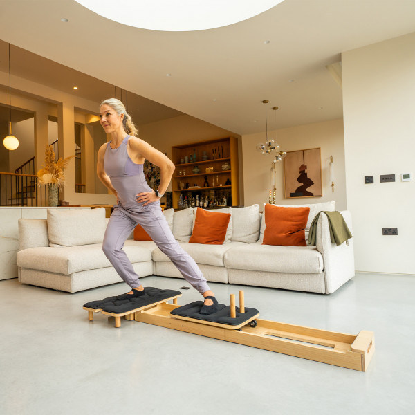 Model performing a lateral lunge on the Gymproluxe Portable Pilates Reformer