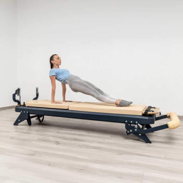 User doing reverse plank on reformer with mat converter installed