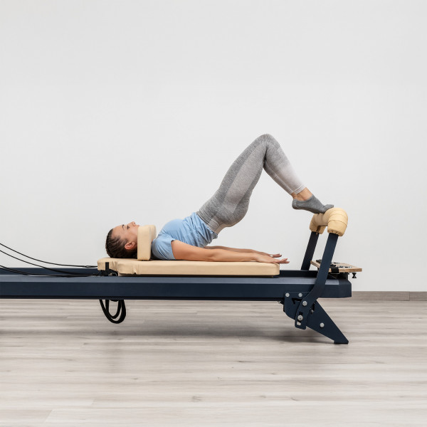 User performing bridge exercise on HEGREN TALMA 62 Pilates Reformer