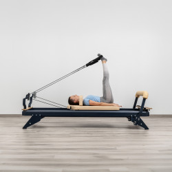 User performing leg extensions with straps on HEGREN TALMA 62 Pilates Reformer