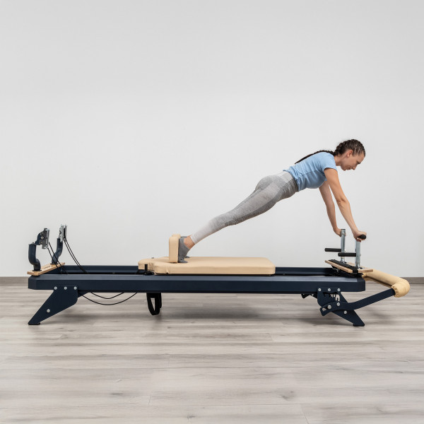 User performing plank exercise using footbar on HEGREN TALMA 62 Pilates Reformer