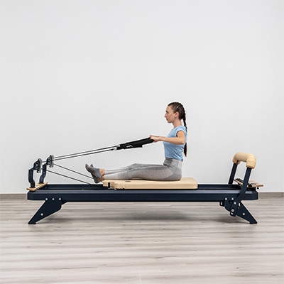 User performing seated row exercise on HEGREN TALMA 62 Pilates Reformer