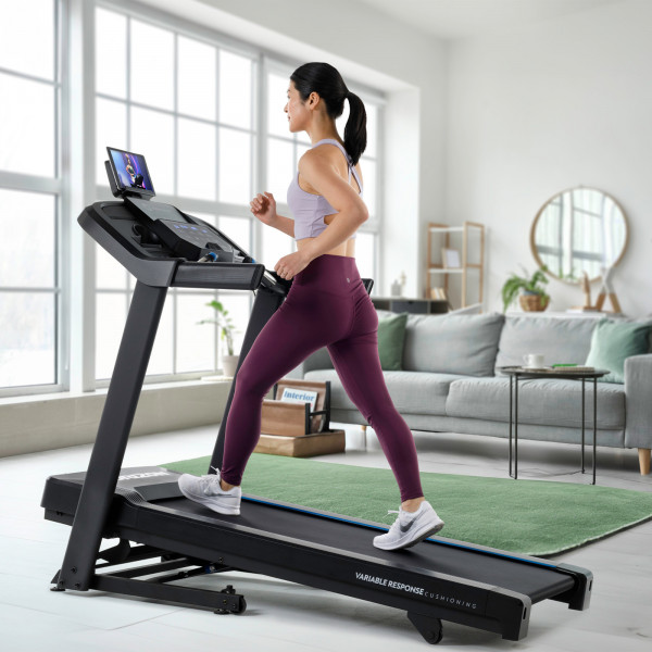 A lifestyle image of a model using the incline on the Horizon 5.0AT Treadmill.