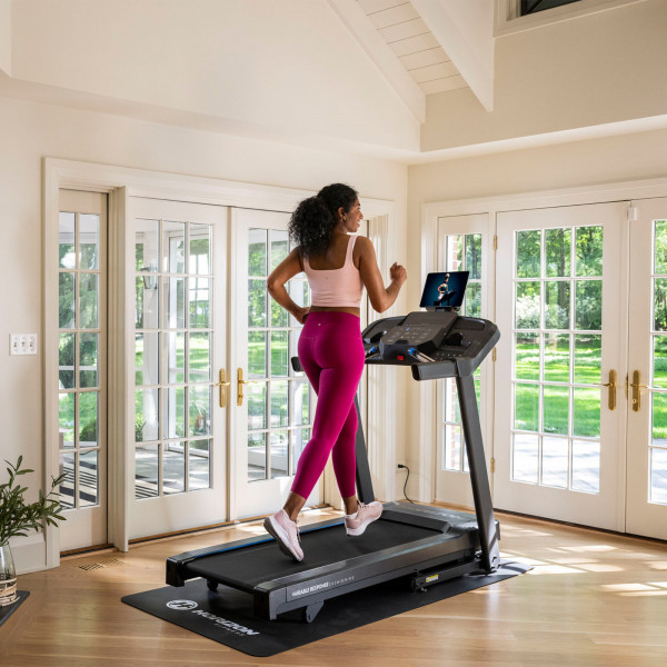 A wide shot lifestyle image of a model running on the Horizon 5.0AT Treadmill.
