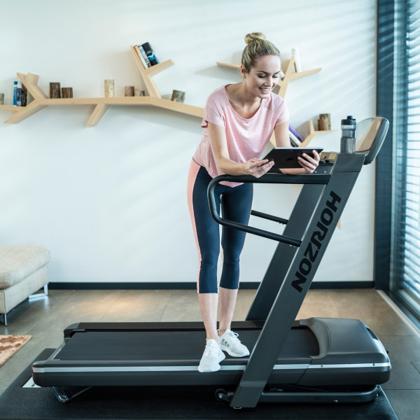 Person adjusting the settings on a tablet before starting their workout on the Horizon Omega Z-02 Treadmill.