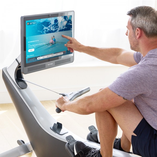 User interacting with the Hydrow Pro Rower console.