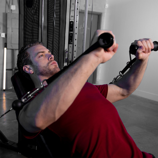 Lifestyle image of a model performing a Cable Chest Press with the Inspire Fitness FT2 Functional Trainer
